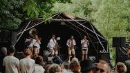 Konligo Fastival event structure with black membrane and outside backdrop hosting a brass band performance at an outdoor festival surrounded by trees, now available on MTN SHOP US.