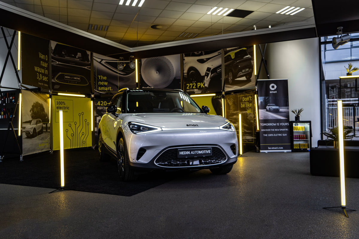 Estructura modular Konligo Luno Wall utilizada como stand de exhibición interior iluminado para Hedin Automotive con un vehículo eléctrico blanco, ahora disponible en MTN SHOP US.